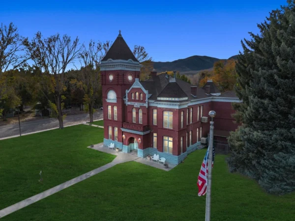 Piute Heritage courthouse lit up at night. There is an American flag in the foreground on the front corner of the lot.