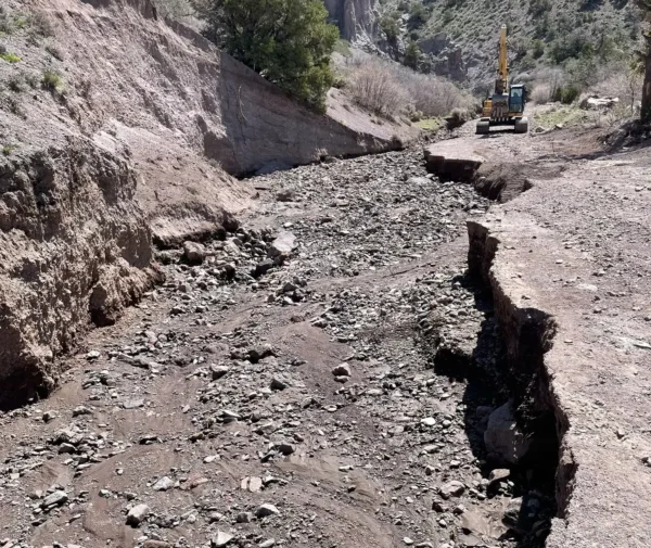 A washed out section of Dry Creek Canyon Road. A backhoe can be seen a distance away, which someone is using to work on the road.