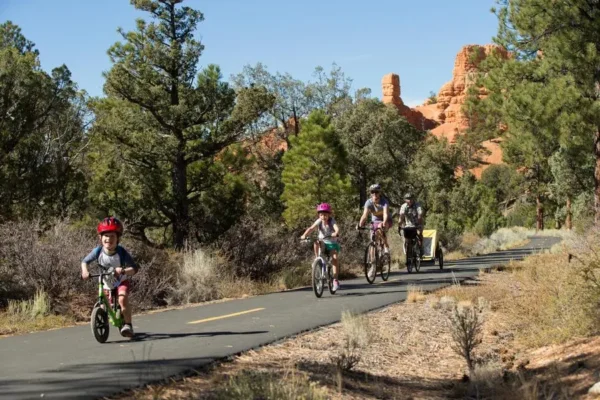 A family of four rides their bikes through the ponderosa trees and red rocks of Red Canyon.