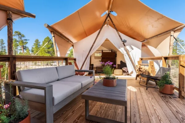A fancy tent-type lodging with nice chairs and couches on a deck.