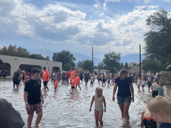 Kids and adults walking around a flooded enclosed area looking for fish.