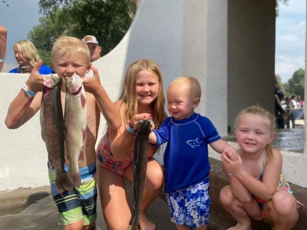 Four little kids proudly hold up the fish they caught.