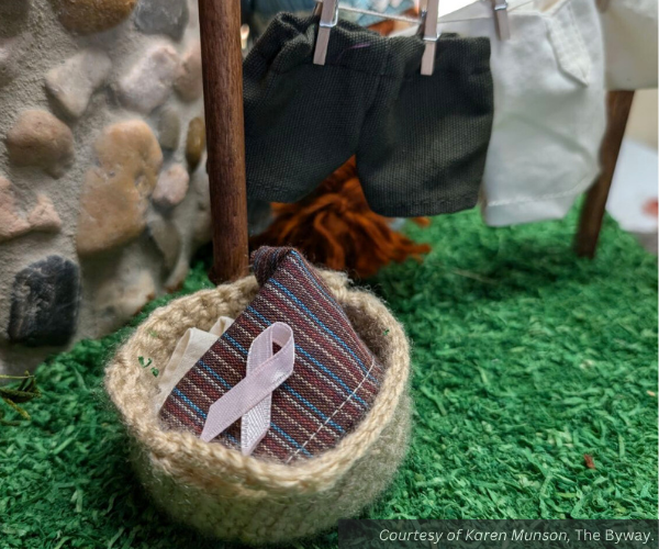 A breast cancer awareness ribbon in a tiny basket of laundry.