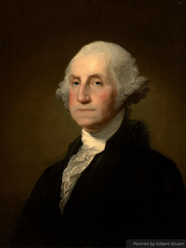 A portrait of George Washington. His white hair and lighted face contrast with the dark background and his black suitcoat.