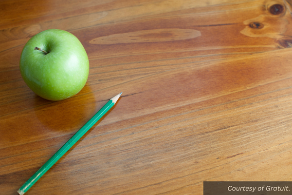 An apple and a pencil on a desk. Courtesy of Gratuit.