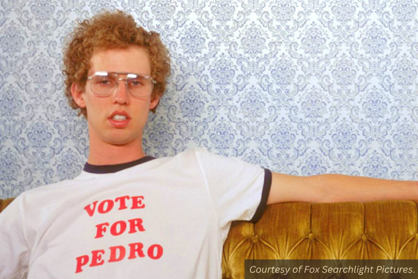 Napoleon (from the movie Napoleon Dynamite) sitting on a couch wearing a "Vote for Pedro" shirt.