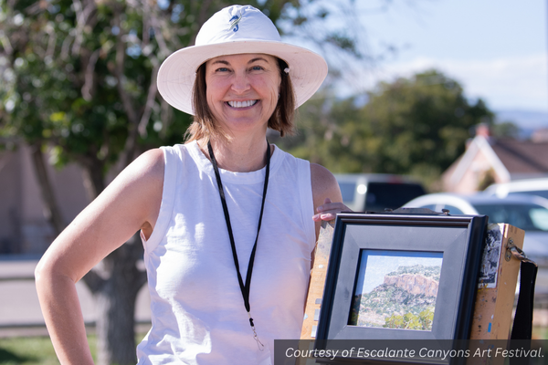 Kristen Featherstone with a framed painting outside in Escalante. Courtesy of Escalante Canyons Art Festival.