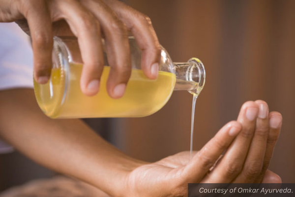 A close-up of a hand pouring oil from a bottle into the other hand. Courtesy of Omkar Ayurveda.