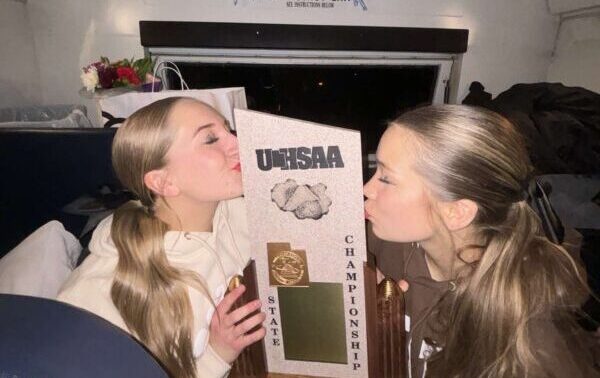 Two Piute cheerleaders kiss their 2024 state championship trophy.