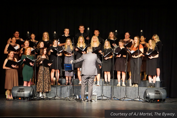 Tyrel Ivie stands on stage in front of the Piute High School choir energetically directing them in a song. Courtesy of AJ Martel, The Byway.