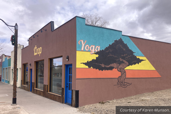 An adobe business building with a colorful mural of a tree on the side of it. Next to the tree is the word "yoga." On the front of the building are the words, "The Loop."