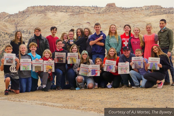 A group of high school kids poses with their two advisors and a year's worth of Byway newspapers. Courtesy of AJ Martel, The Byway.