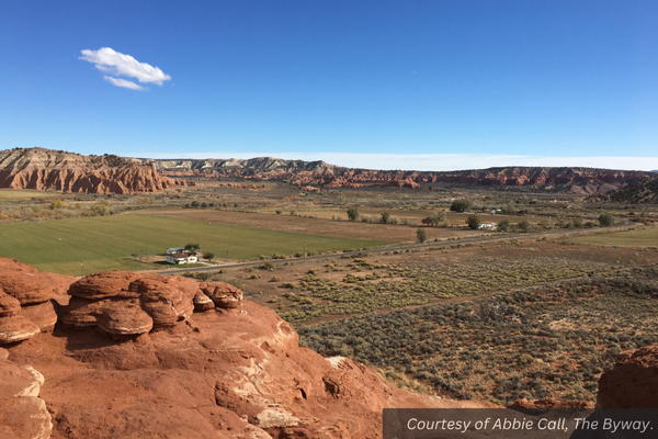 Green fields, red rocks, and a couple of cows in Cannonville, Utah. Courtesy of Abbie Call, The Byway.