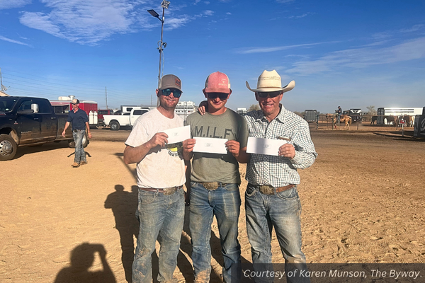 Flint, Draker, and Link Chynoweth show off their envelopes of awards at a rodeo.